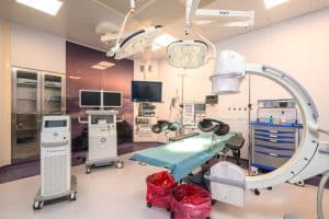 Panneau d'équipements médicaux dans une salle d'urologie moderne avec un lit d'examen, moniteurs et appareils pour interventions urologiques.